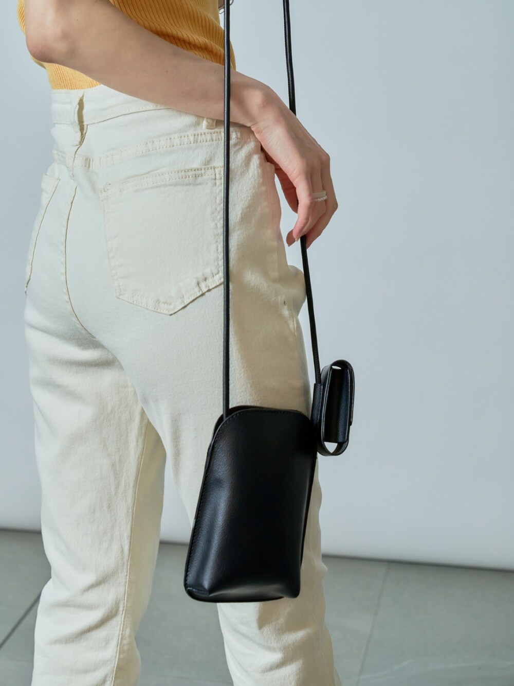 ホワイト系のデニムパンツ、イエロー系のタンクトップ、ブラック系のサンダルを着用したレディースの夏コーディネートの4枚目の写真