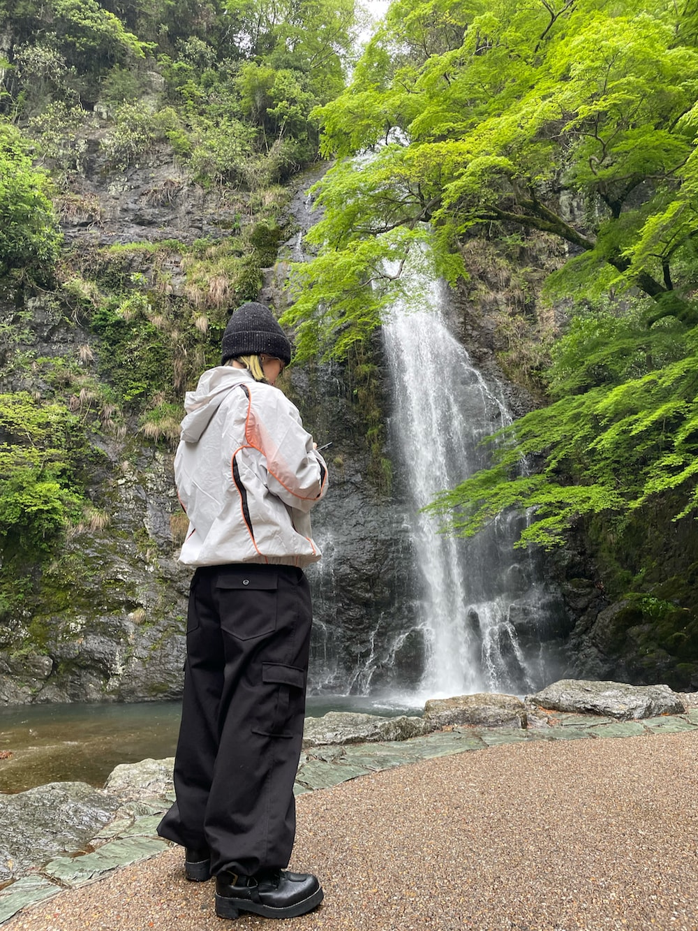 ブラック系のカーゴパンツ、ホワイト系のナイロンジャケット、ブラック系のニットキャップ/ビーニーを着用したレディースの夏コーディネートの2枚目の写真