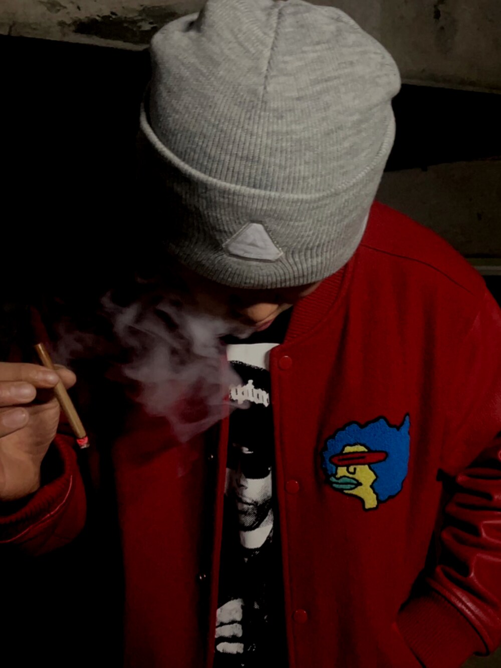 レッド系のスタジャン、ブルー系のデニムパンツ、ブラック系のスニーカーを着用したメンズの秋コーディネートの2枚目の写真