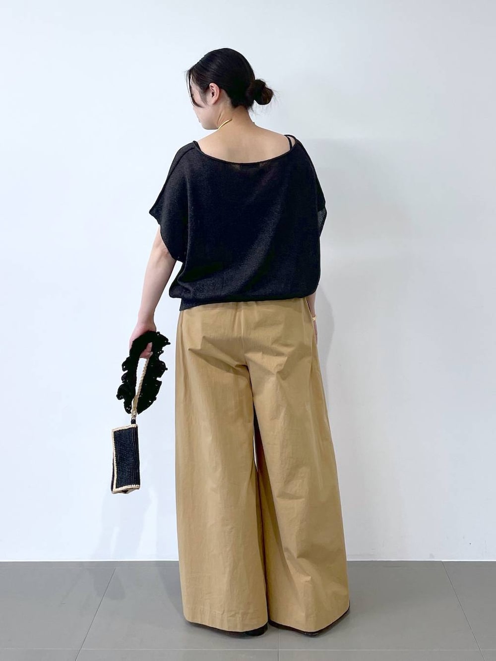 ブラック系のハンドバッグ、ブラック系のパンプス、グレー系のニット/セーターを着用したレディースの春コーディネートの3枚目の写真