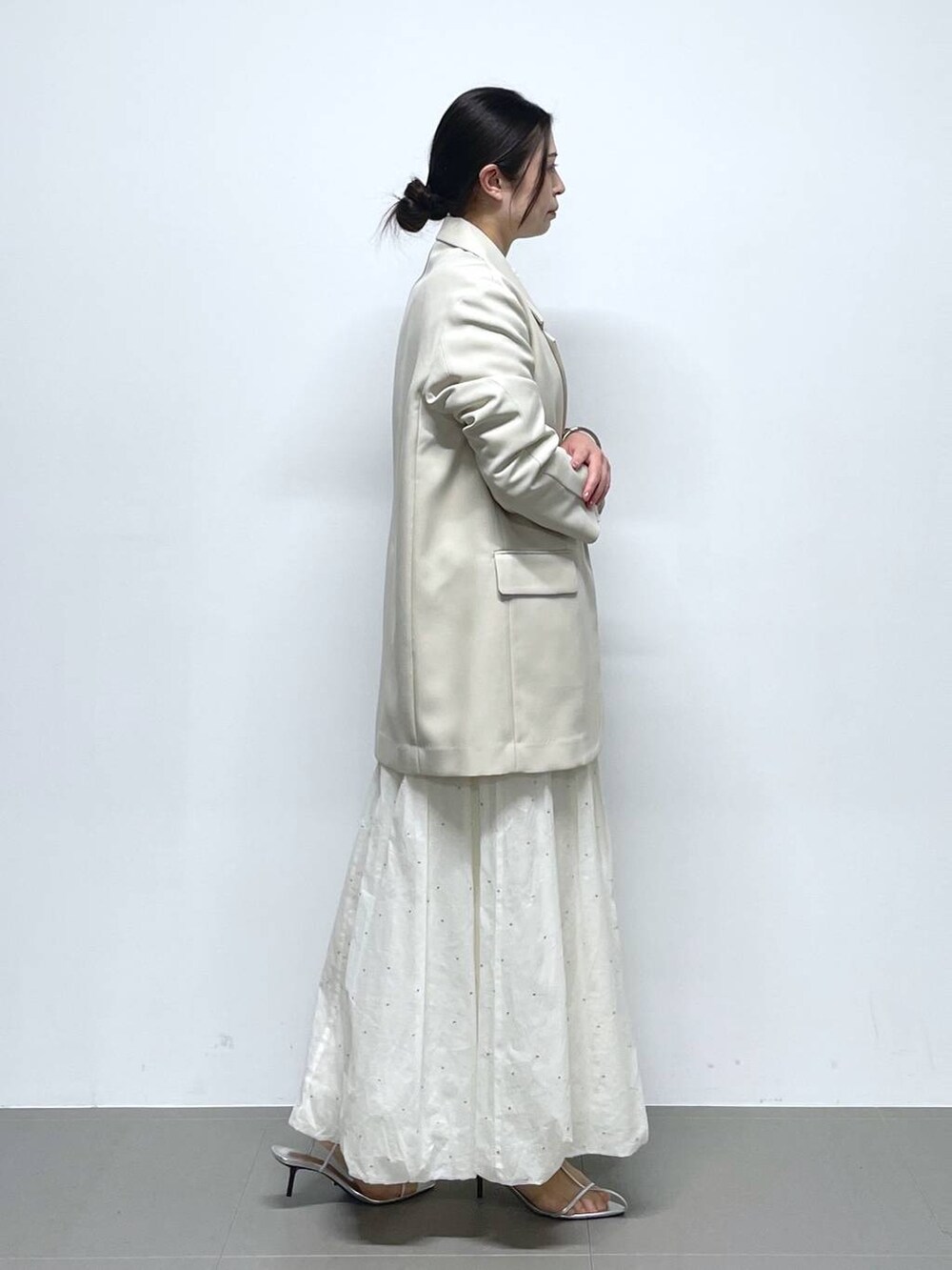 ホワイト系のスカート、ホワイト系のニット/セーター、ベージュ系のテーラードジャケットを着用したレディースの冬コーディネートの2枚目の写真