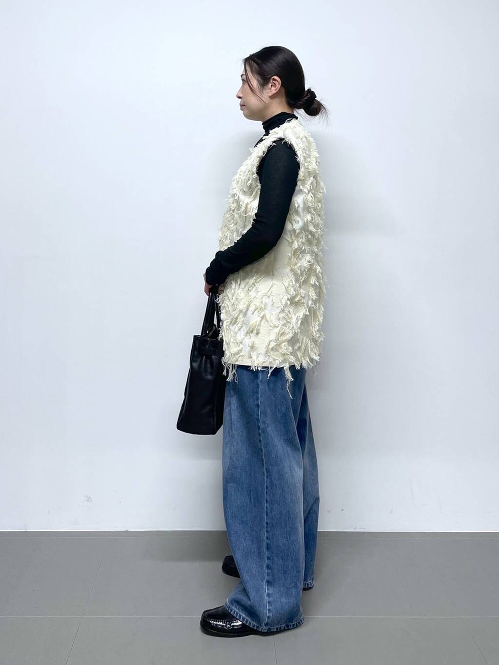 ブルー系のデニムパンツ、ブラック系のTシャツ/カットソー、ホワイト系のベストを着用したレディースの冬コーディネートの2枚目の写真