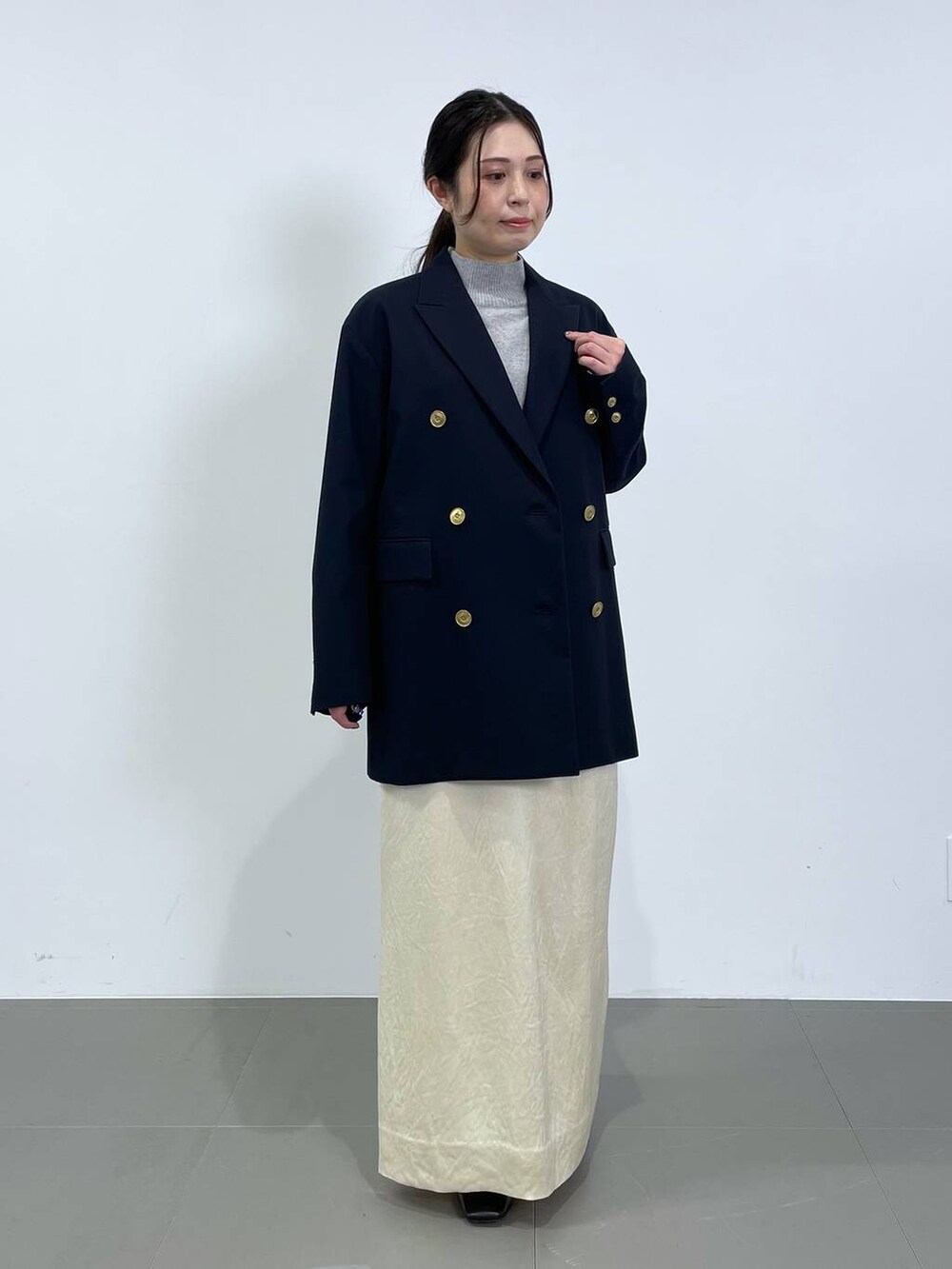 ホワイト系のスカート、ブルー系のテーラードジャケット、グレー系のニット/セーターを着用したレディースの冬コーディネートの4枚目の写真