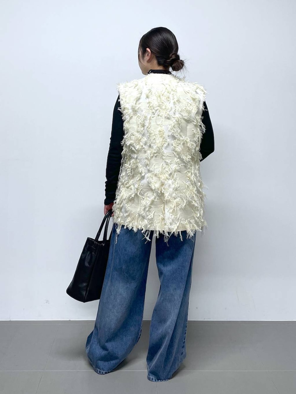 ブルー系のデニムパンツ、ブラック系のTシャツ/カットソー、ホワイト系のベストを着用したレディースの冬コーディネートの3枚目の写真