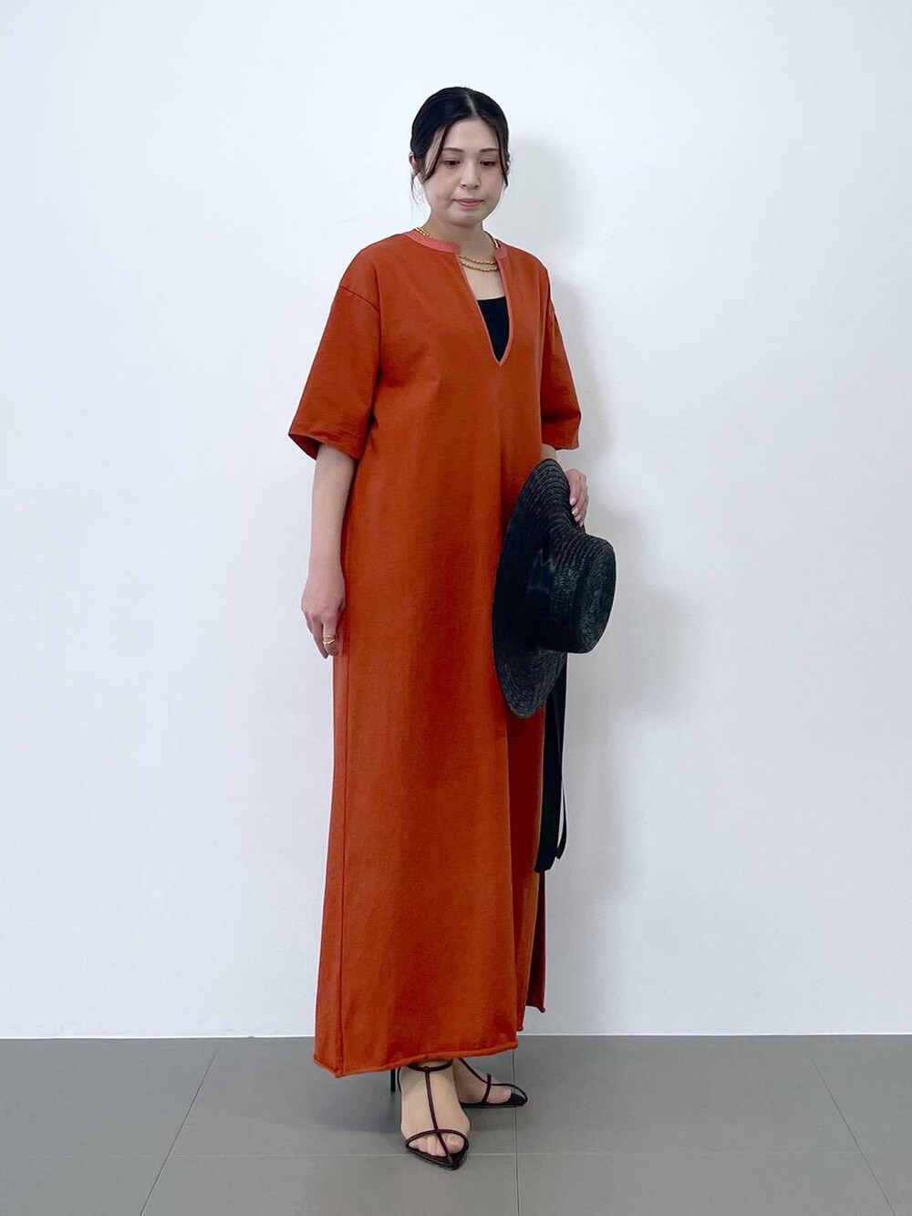 ブラック系のサンダル、オレンジ系のワンピース、ブラウン系のネックレスを着用したレディースの春コーディネートの5枚目の写真