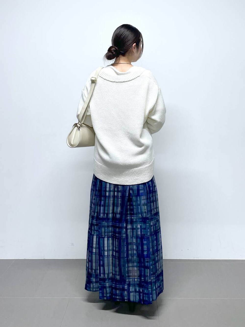 ホワイト系のショルダーバッグ、ホワイト系のTシャツ/カットソー、ブルー系のスカートを着用したレディースの冬コーディネートの3枚目の写真