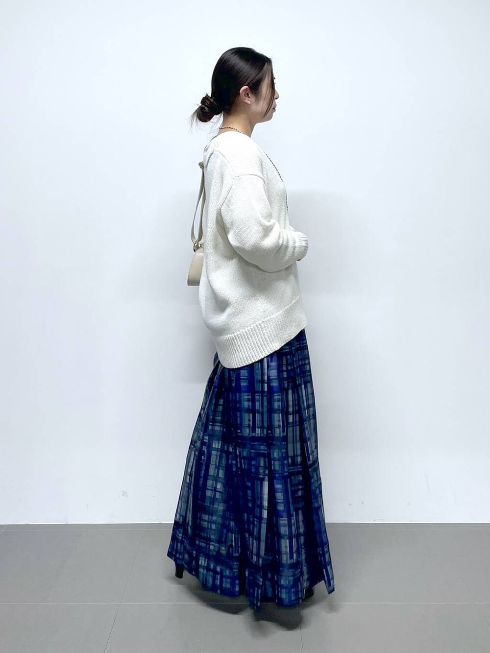 ホワイト系のショルダーバッグ、ホワイト系のTシャツ/カットソー、ブルー系のスカートを着用したレディースの冬コーディネートの2枚目の写真