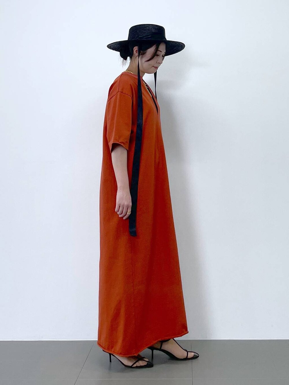 ブラック系のサンダル、オレンジ系のワンピース、ブラウン系のネックレスを着用したレディースの春コーディネートの2枚目の写真