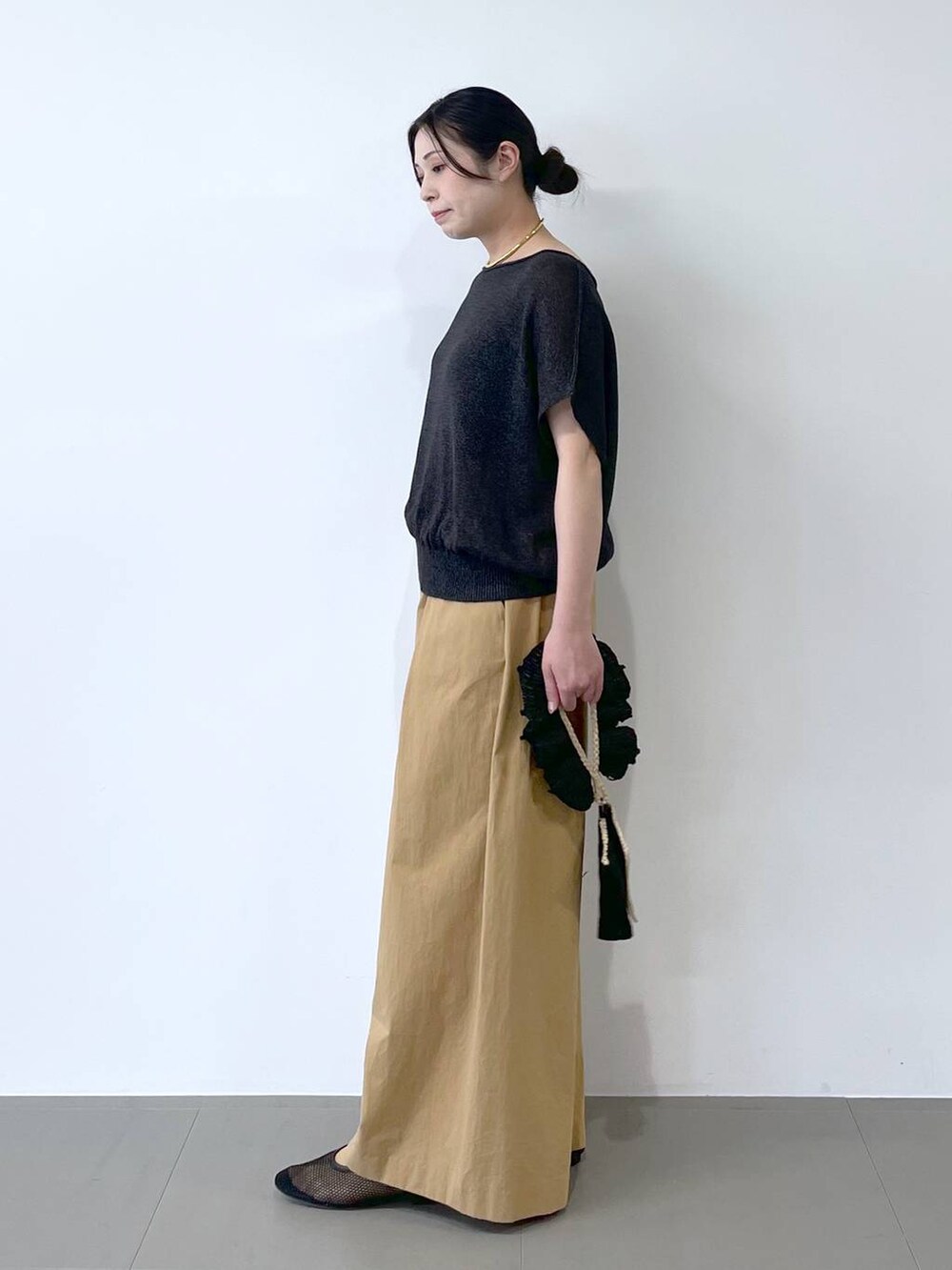 ブラック系のハンドバッグ、ブラック系のパンプス、グレー系のニット/セーターを着用したレディースの春コーディネートの2枚目の写真