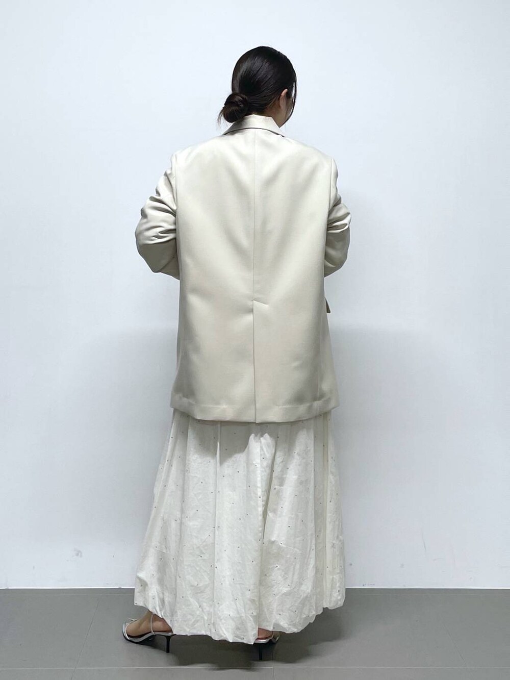 ホワイト系のスカート、ホワイト系のニット/セーター、ベージュ系のテーラードジャケットを着用したレディースの冬コーディネートの3枚目の写真