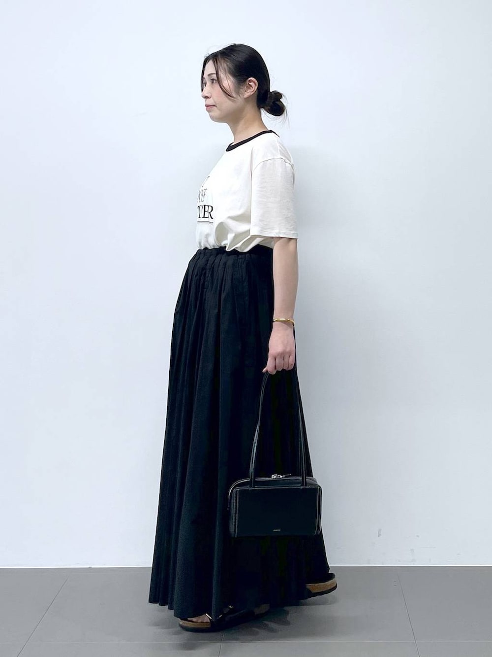 ブラック系のサンダル、ホワイト系のTシャツ/カットソーを着用したレディースの春コーディネートの2枚目の写真