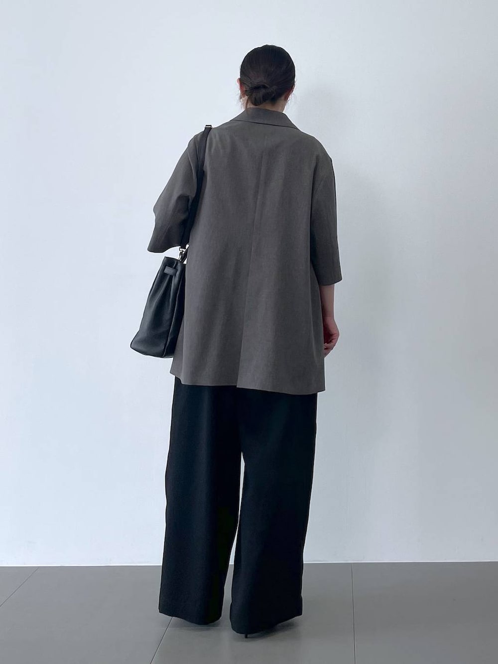 ブラック系のハンドバッグ、ブラック系のサンダル、ホワイト系のTシャツ/カットソーを着用したレディースの春コーディネートの3枚目の写真