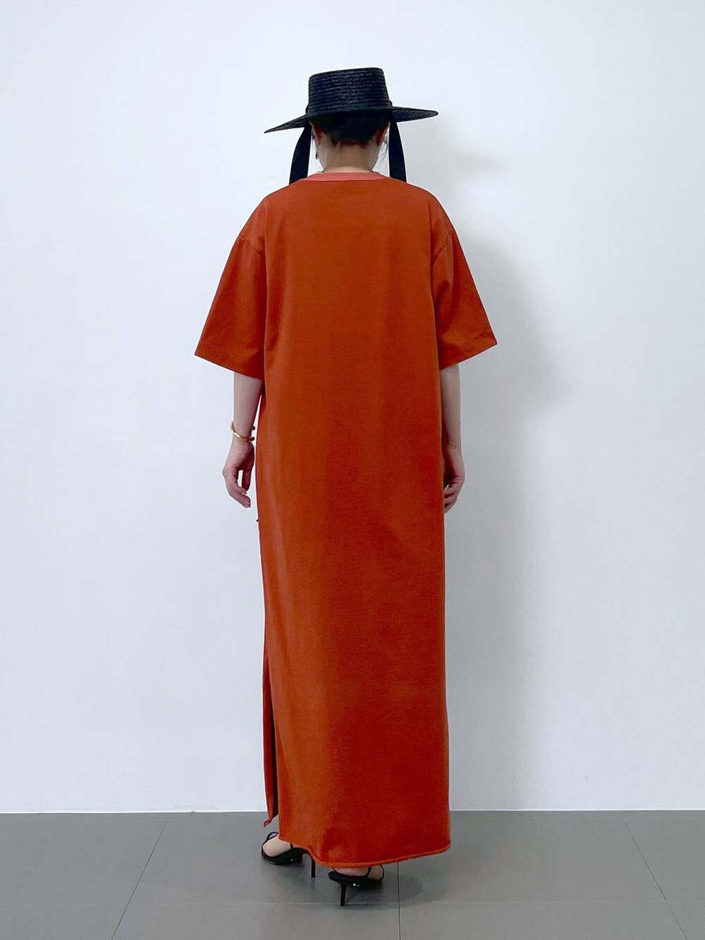 ブラック系のサンダル、オレンジ系のワンピース、ブラウン系のネックレスを着用したレディースの春コーディネートの3枚目の写真