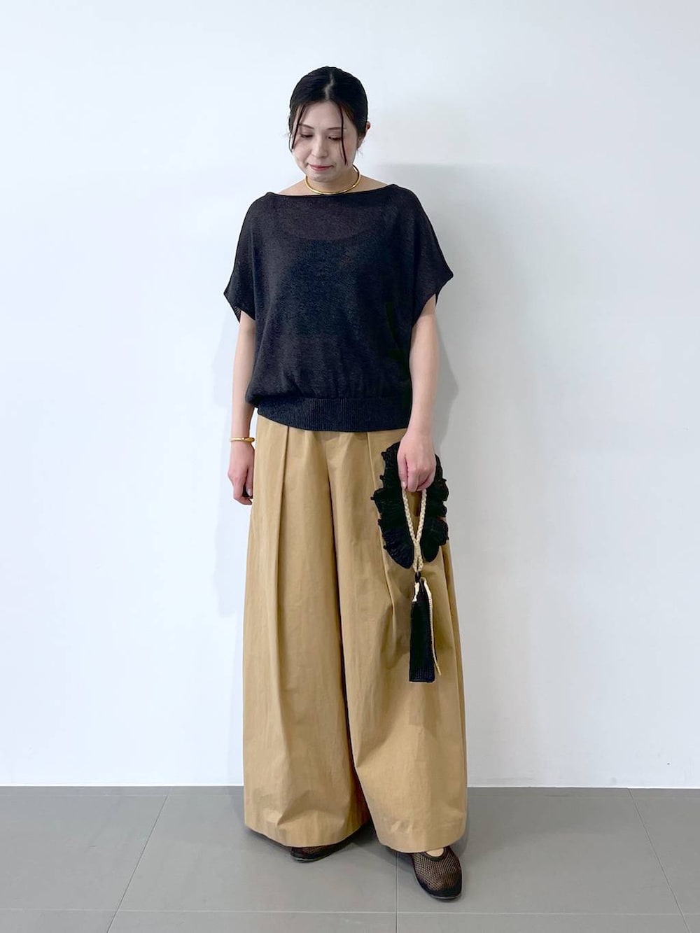 ブラック系のハンドバッグ、ブラック系のパンプス、グレー系のニット/セーターを着用したレディースの春コーディネートの4枚目の写真