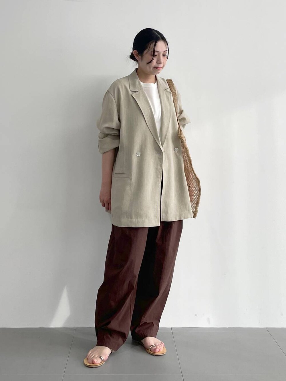 ベージュ系のトートバッグ、ベージュ系のサンダル、ホワイト系のタンクトップを着用したレディースの春コーディネートの2枚目の写真