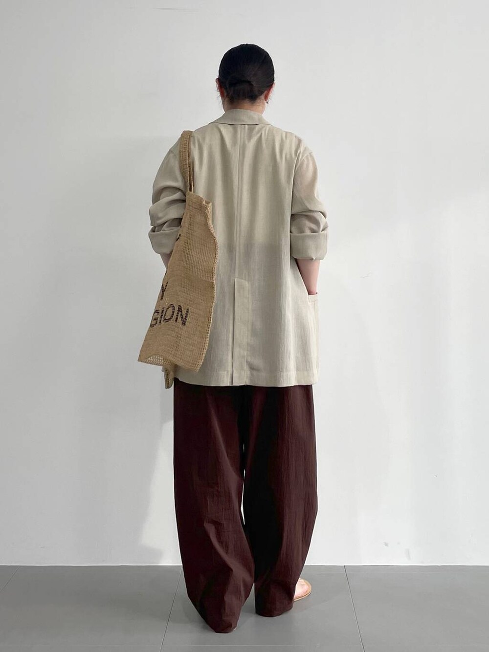 ベージュ系のトートバッグ、ベージュ系のサンダル、ホワイト系のタンクトップを着用したレディースの春コーディネートの4枚目の写真