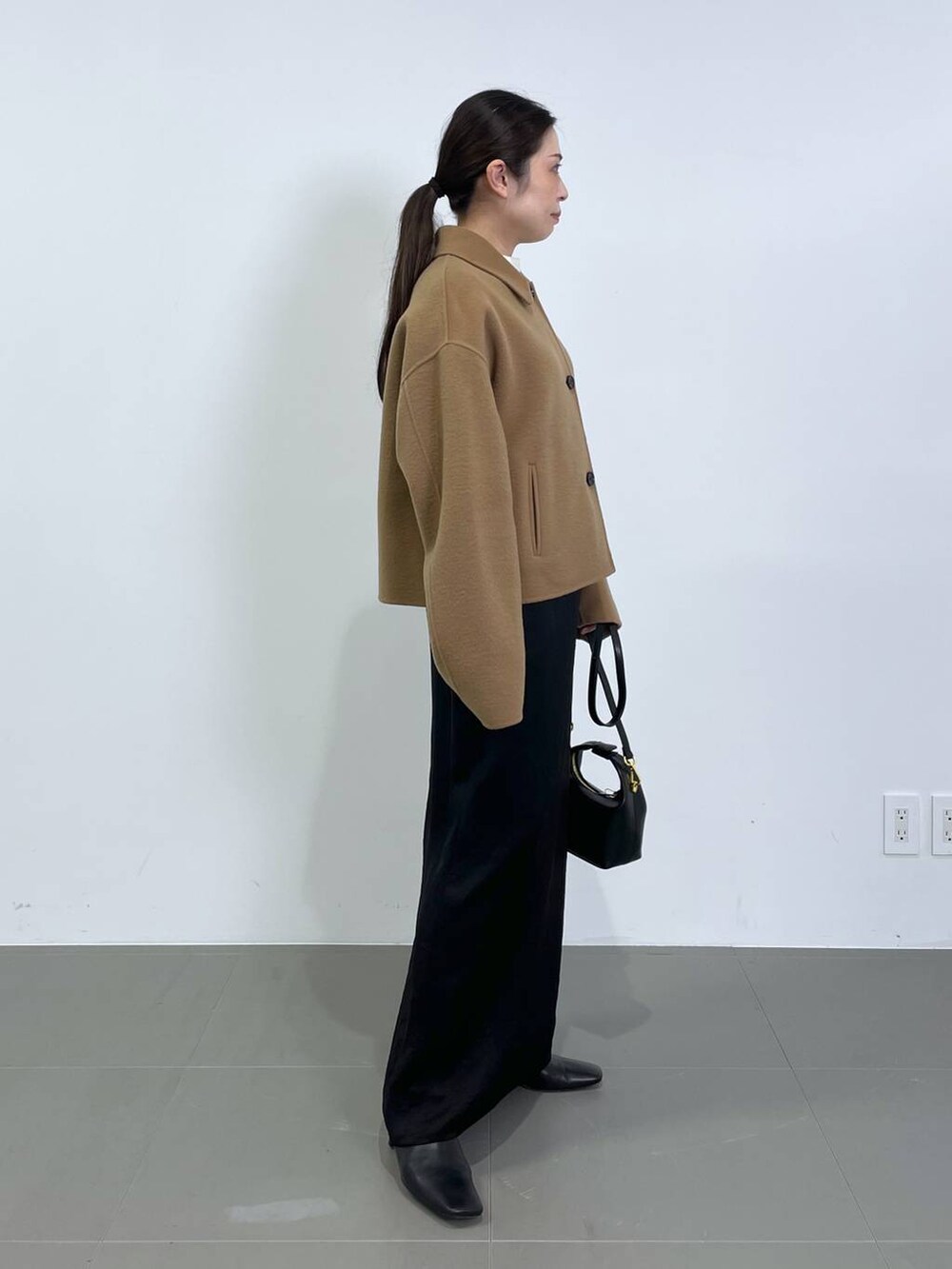 ブラック系のスカート、ベージュ系のその他アウター、ホワイト系のニット/セーターを着用したレディースの冬コーディネートの2枚目の写真