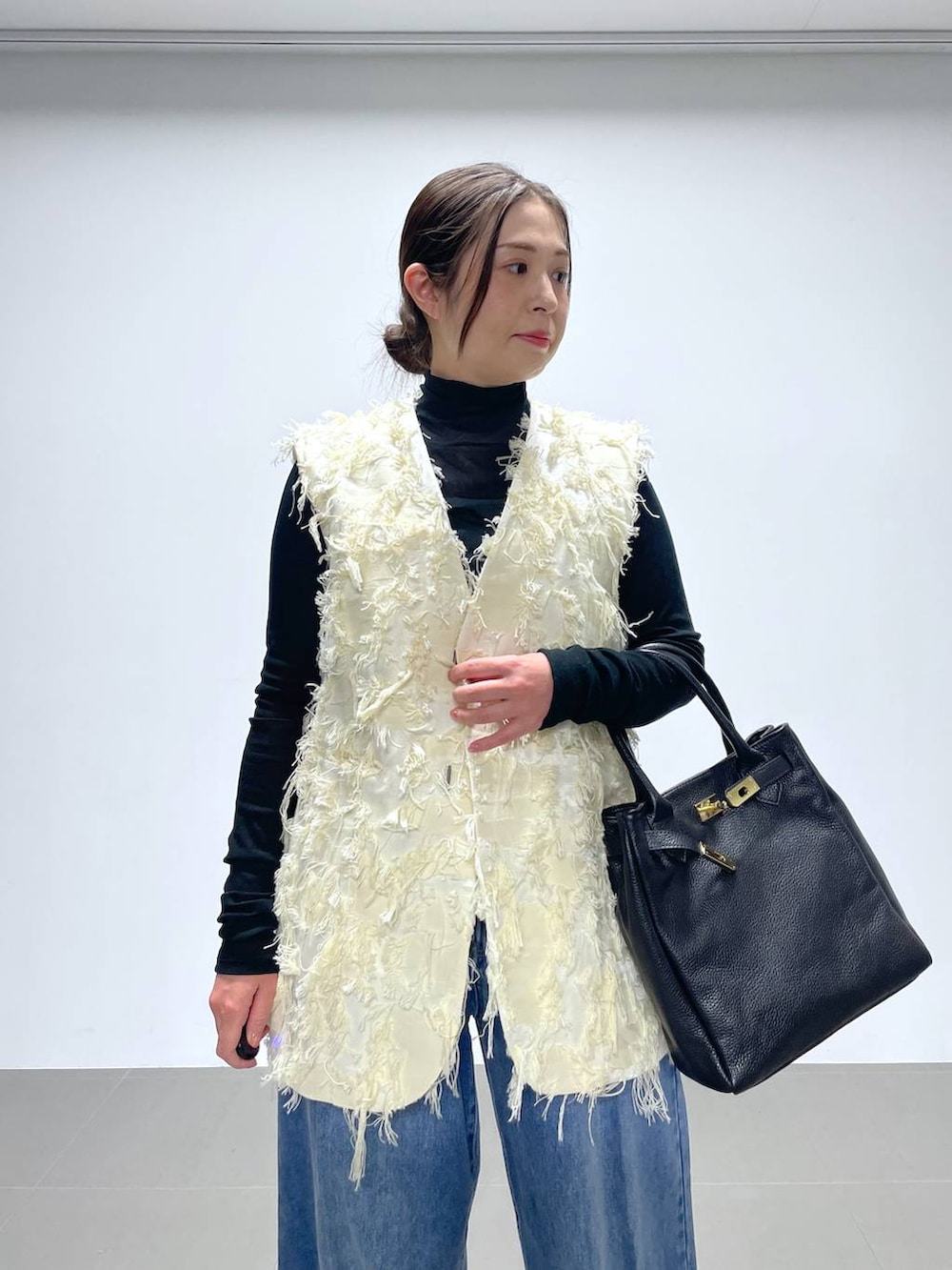 ブルー系のデニムパンツ、ブラック系のTシャツ/カットソー、ホワイト系のベストを着用したレディースの冬コーディネートの4枚目の写真