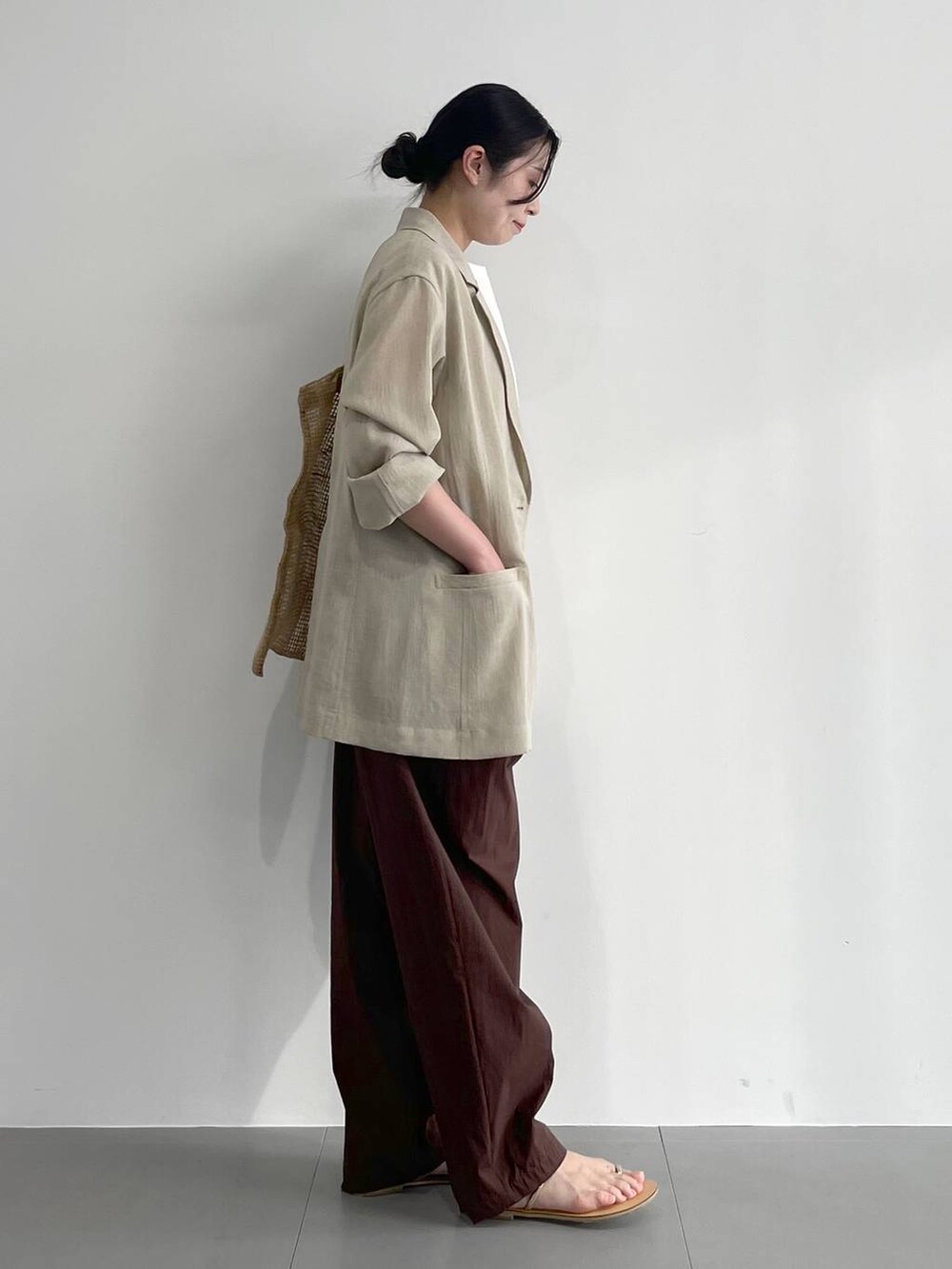 ベージュ系のトートバッグ、ベージュ系のサンダル、ホワイト系のタンクトップを着用したレディースの春コーディネートの3枚目の写真