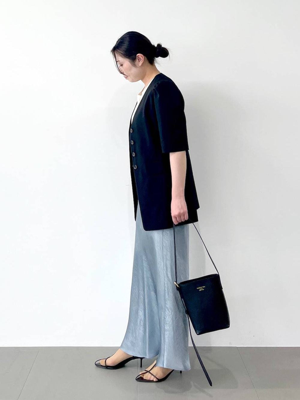 ブラック系のサンダル、ブラック系のショルダーバッグ、ブルー系のスカートを着用したレディースの春コーディネートの2枚目の写真