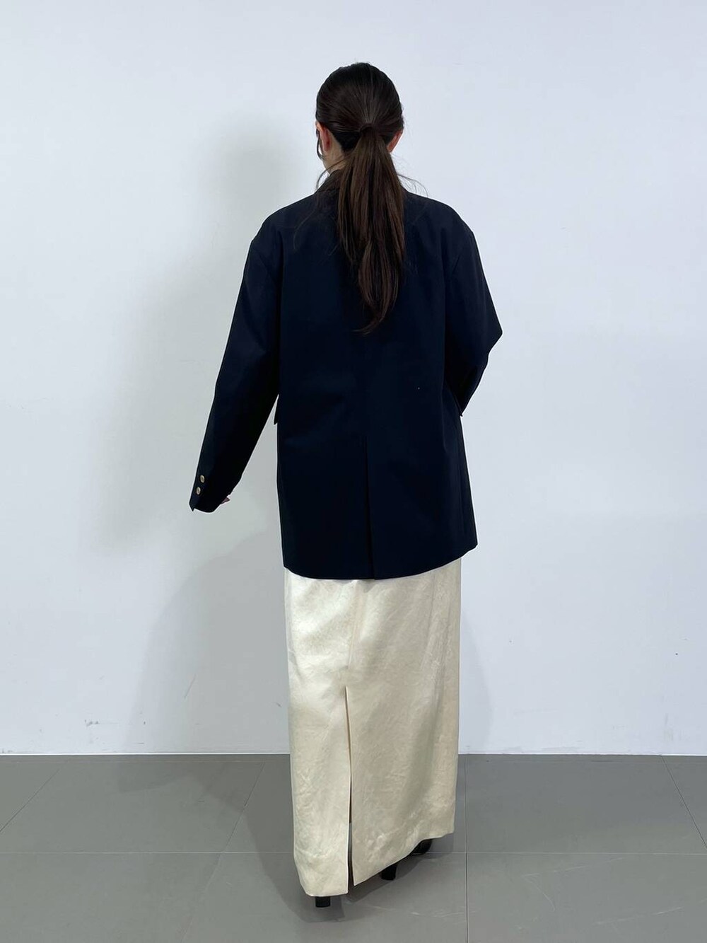 ホワイト系のスカート、ブルー系のテーラードジャケット、グレー系のニット/セーターを着用したレディースの冬コーディネートの3枚目の写真