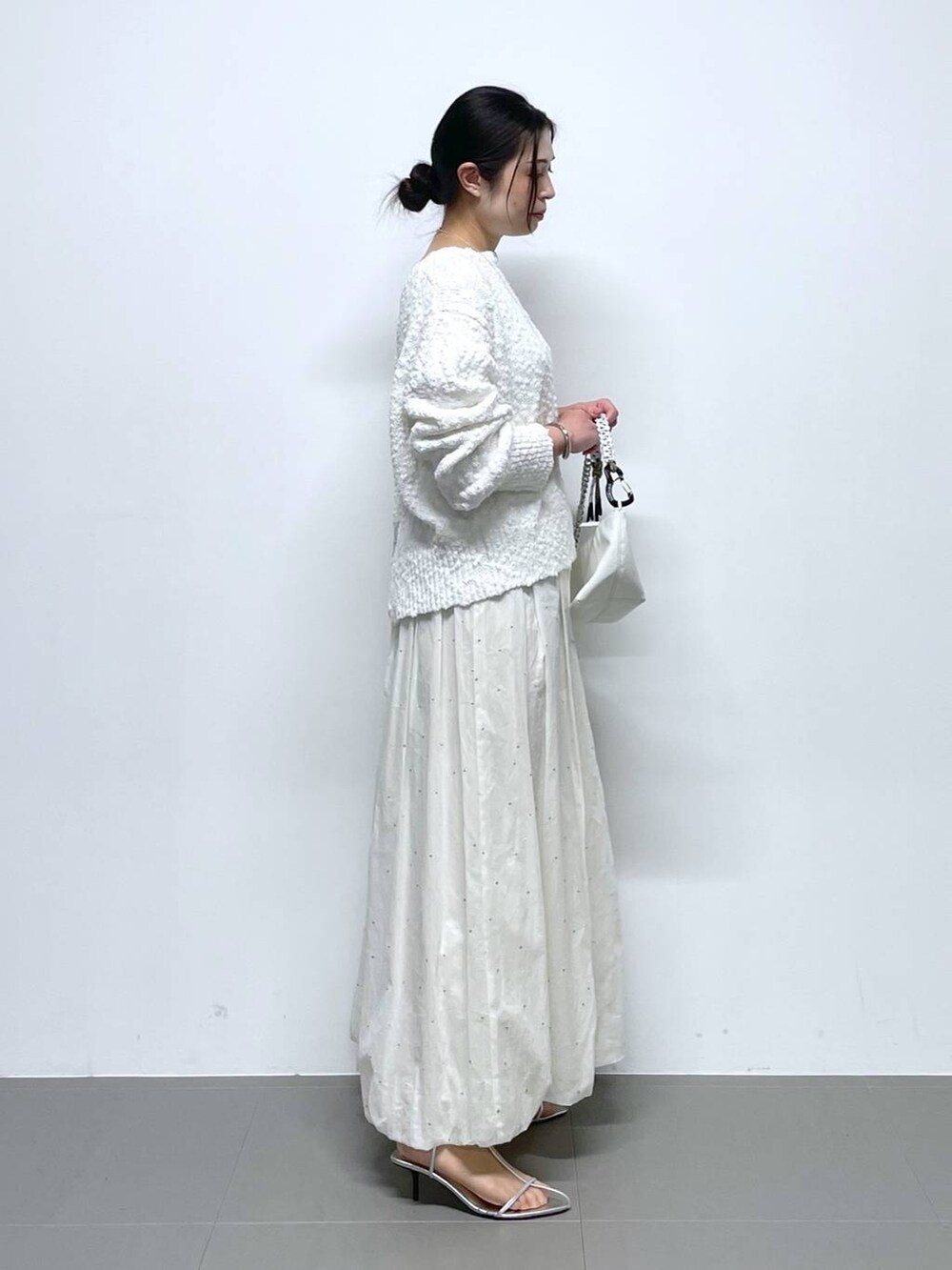 ホワイト系のショルダーバッグ、ホワイト系のニット/セーター、ホワイト系のスカートを着用したレディースの冬コーディネートの2枚目の写真