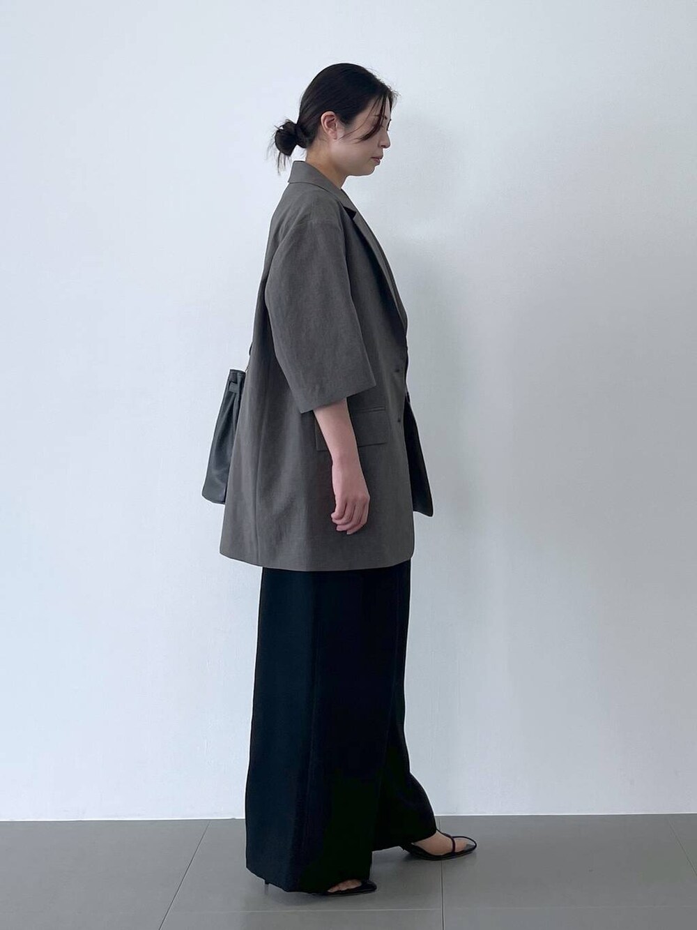 ブラック系のハンドバッグ、ブラック系のサンダル、ホワイト系のTシャツ/カットソーを着用したレディースの春コーディネートの2枚目の写真