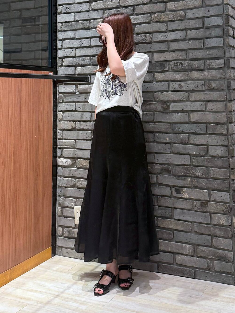 ブラック系のサンダル、ベージュ系のTシャツ/カットソー、ブラック系のスカートを着用したレディースの夏コーディネートの2枚目の写真