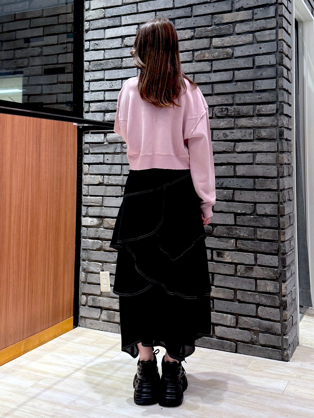 ピンク系のスウェット、ブラック系のスカート、ブラック系のスニーカーを着用したレディースの春コーディネートの3枚目の写真