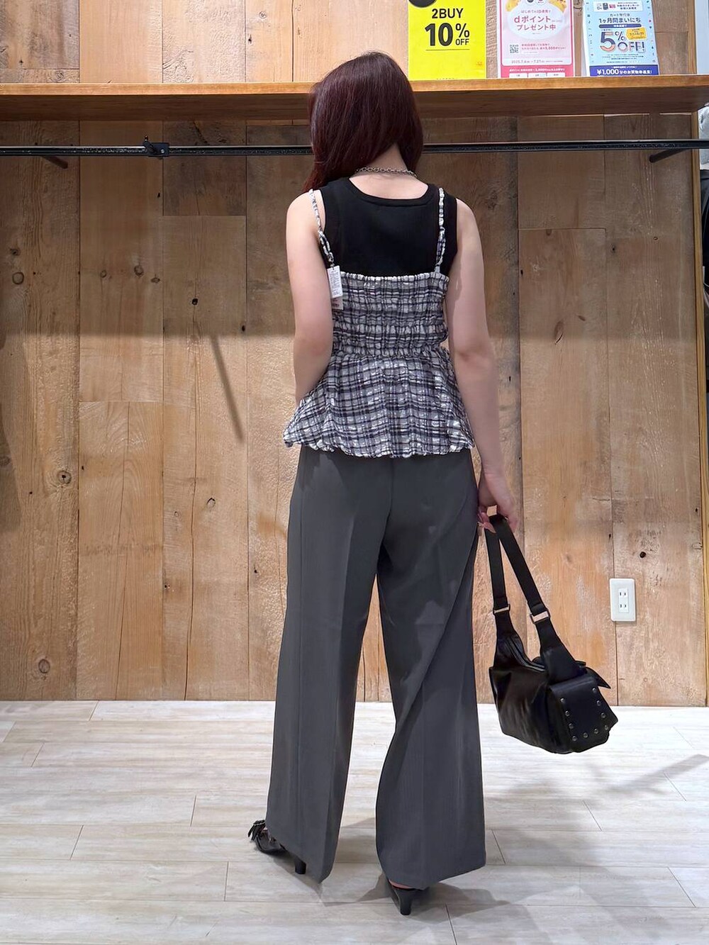 ブラック系のサンダル、グレー系のスラックス、ブラック系のショルダーバッグを着用したレディースの夏コーディネートの3枚目の写真