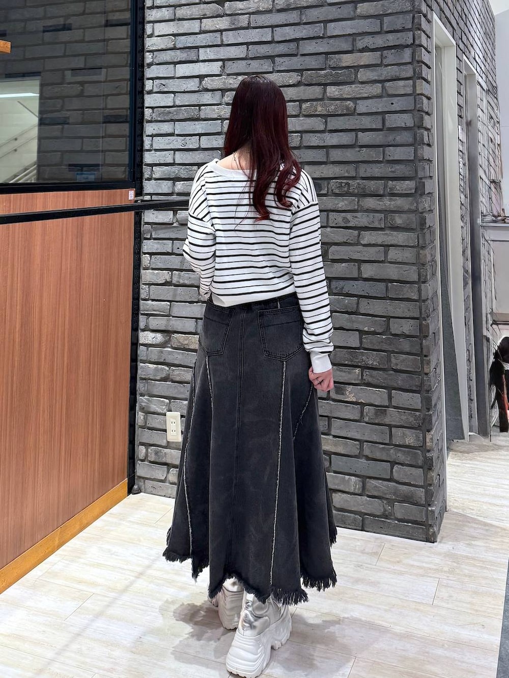 ホワイト系のブーツ、ブラック系のデニムスカート、ホワイト系のTシャツ/カットソーを着用したレディースの冬コーディネートの3枚目の写真