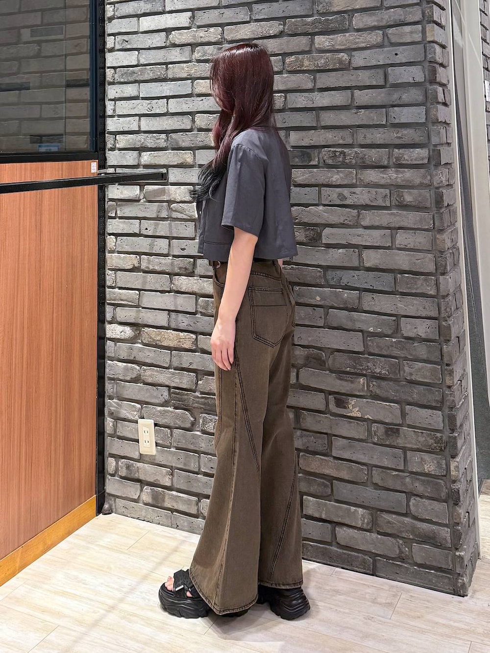 グレー系のテーラードジャケット、ブラウン系のデニムパンツ、ブラック系のサンダルを着用したレディースの夏コーディネートの3枚目の写真