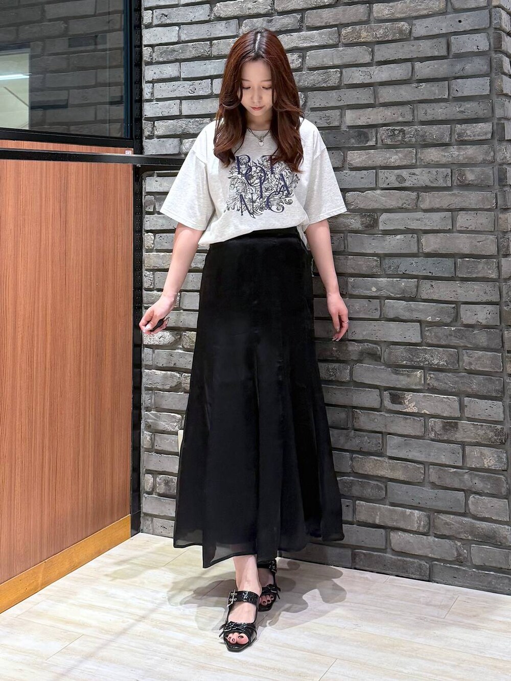 ブラック系のサンダル、ベージュ系のTシャツ/カットソー、ブラック系のスカートを着用したレディースの夏コーディネートの5枚目の写真