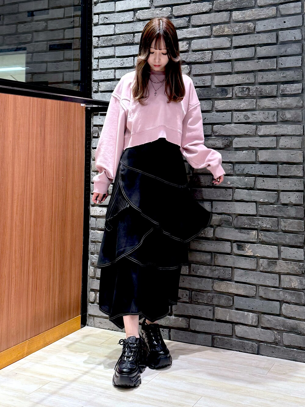 ピンク系のスウェット、ブラック系のスカート、ブラック系のスニーカーを着用したレディースの春コーディネートの5枚目の写真