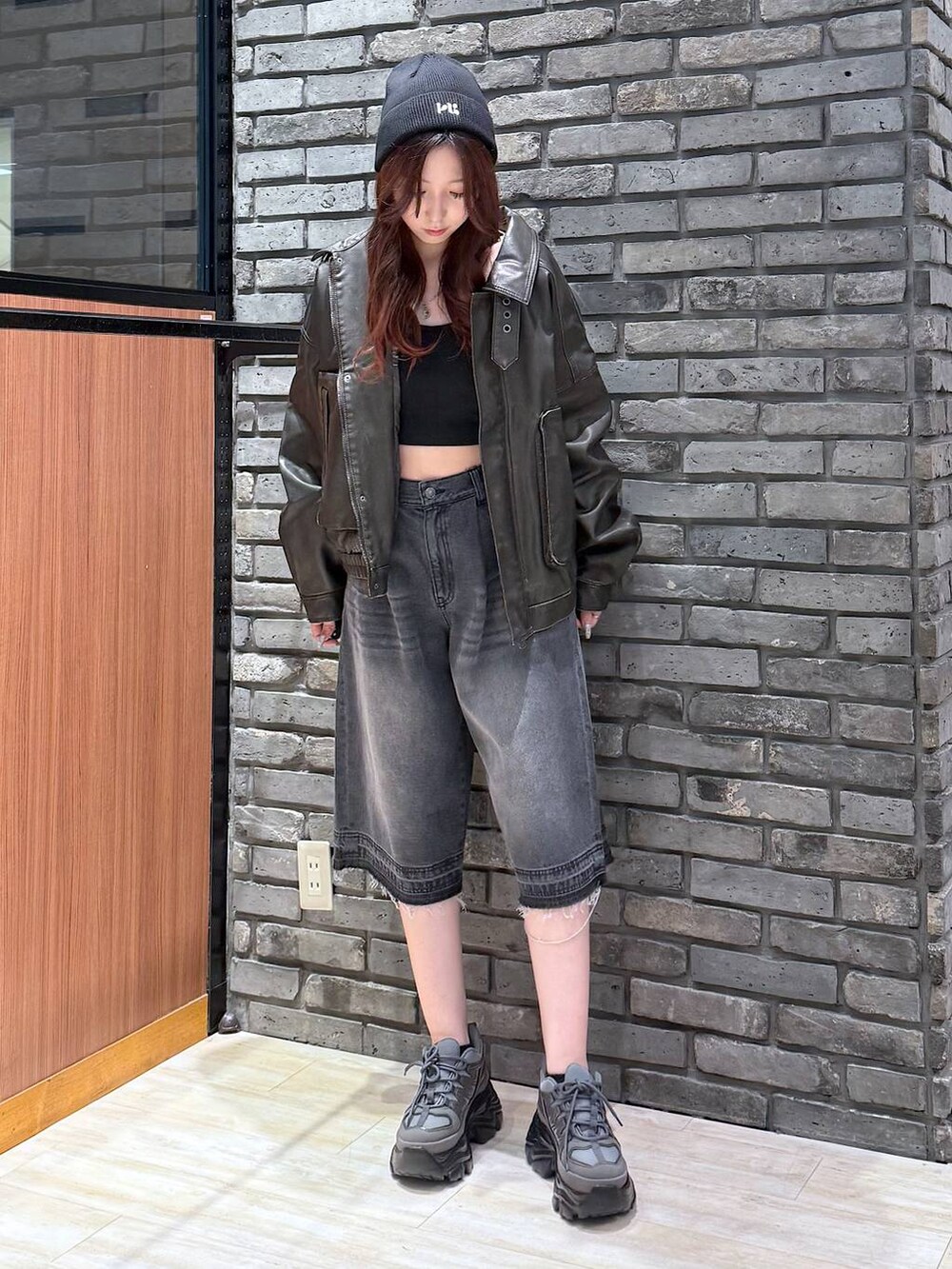 グレー系のスニーカー、ブラック系のデニムパンツ、ブラック系のブルゾンを着用したレディースの秋コーディネートの2枚目の写真