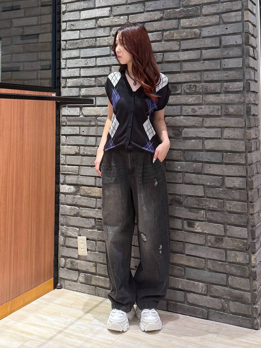 ホワイト系のスニーカー、ブラック系のデニムパンツ、ブラック系のベストを着用したレディースの秋コーディネートの2枚目の写真