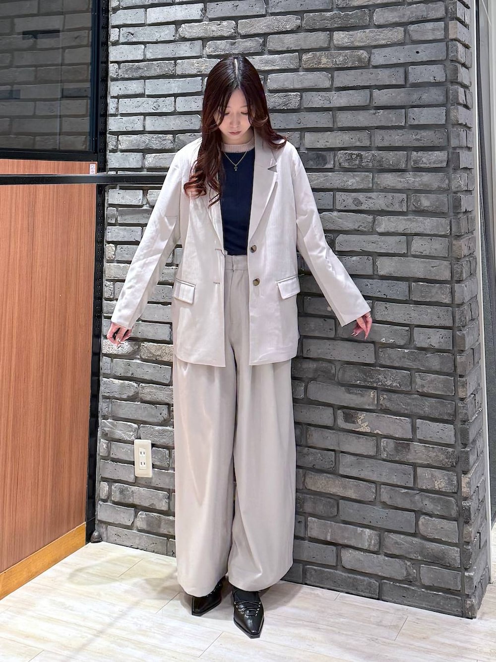 グレー系のテーラードジャケット、ベージュ系のデニムパンツ、ブラック系のサンダルを着用したレディースの冬コーディネートの2枚目の写真