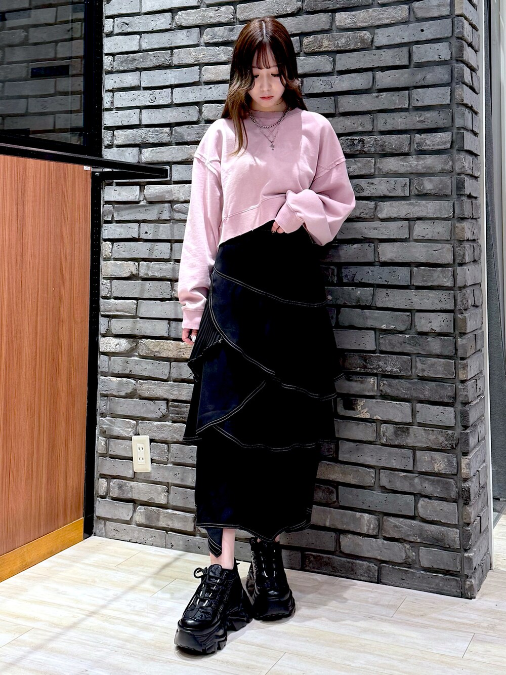 ピンク系のスウェット、ブラック系のスカート、ブラック系のスニーカーを着用したレディースの春コーディネートの2枚目の写真