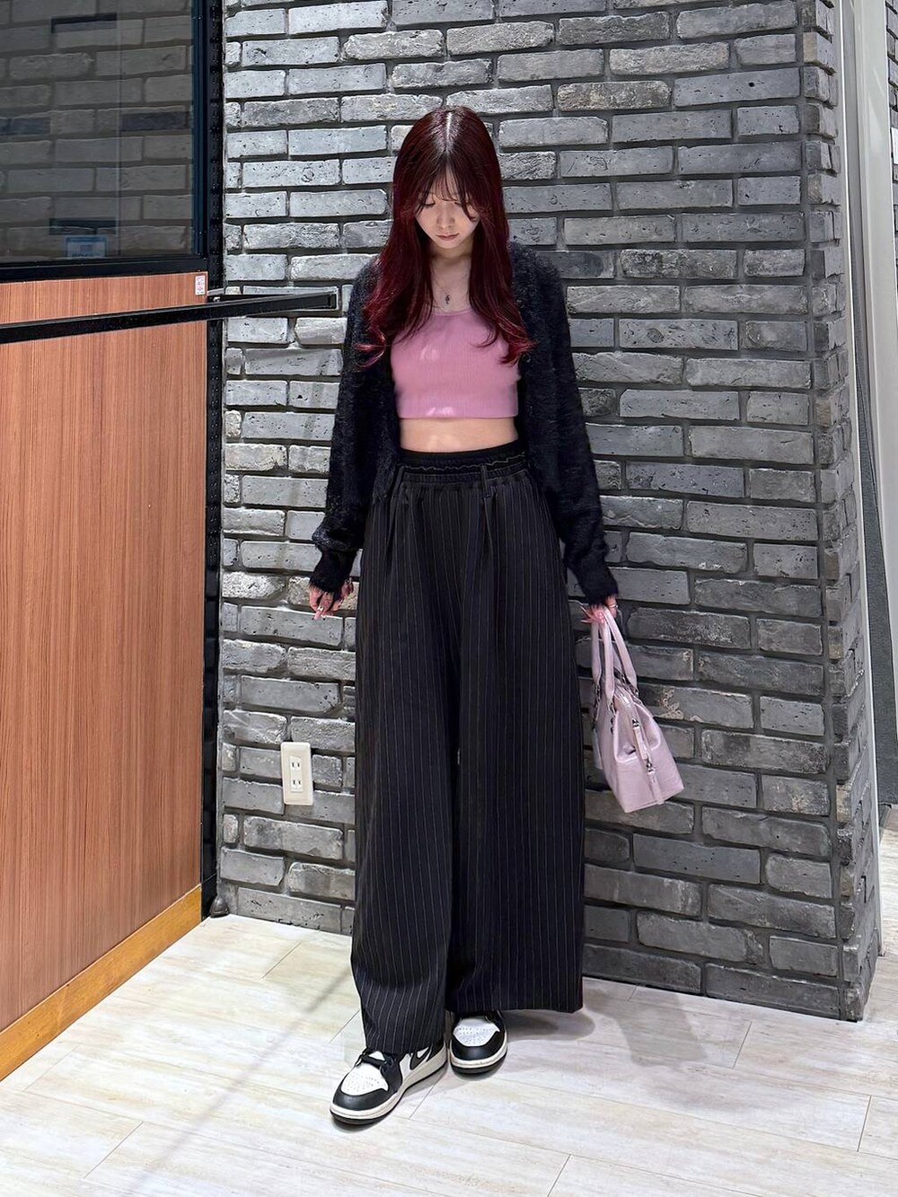 ピンク系のハンドバッグ、ブラック系のスラックス、ブラック系のニット/セーターを着用したレディースの冬コーディネートの4枚目の写真