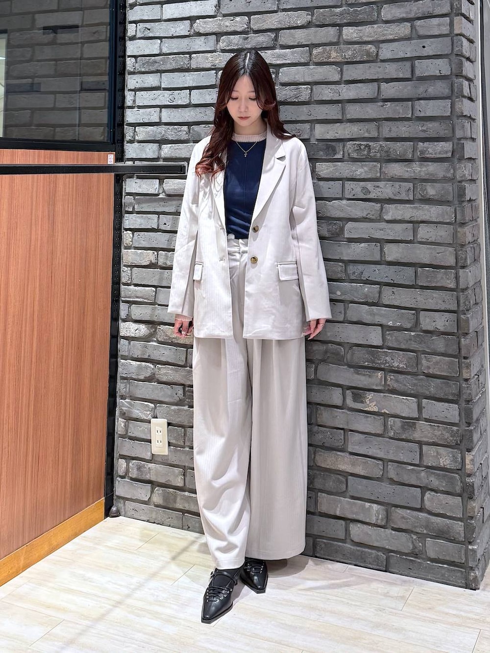 グレー系のテーラードジャケット、ベージュ系のデニムパンツ、ブラック系のサンダルを着用したレディースの冬コーディネートの4枚目の写真