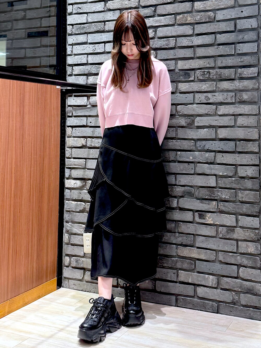 ピンク系のスウェット、ブラック系のスカート、ブラック系のスニーカーを着用したレディースの春コーディネートの4枚目の写真