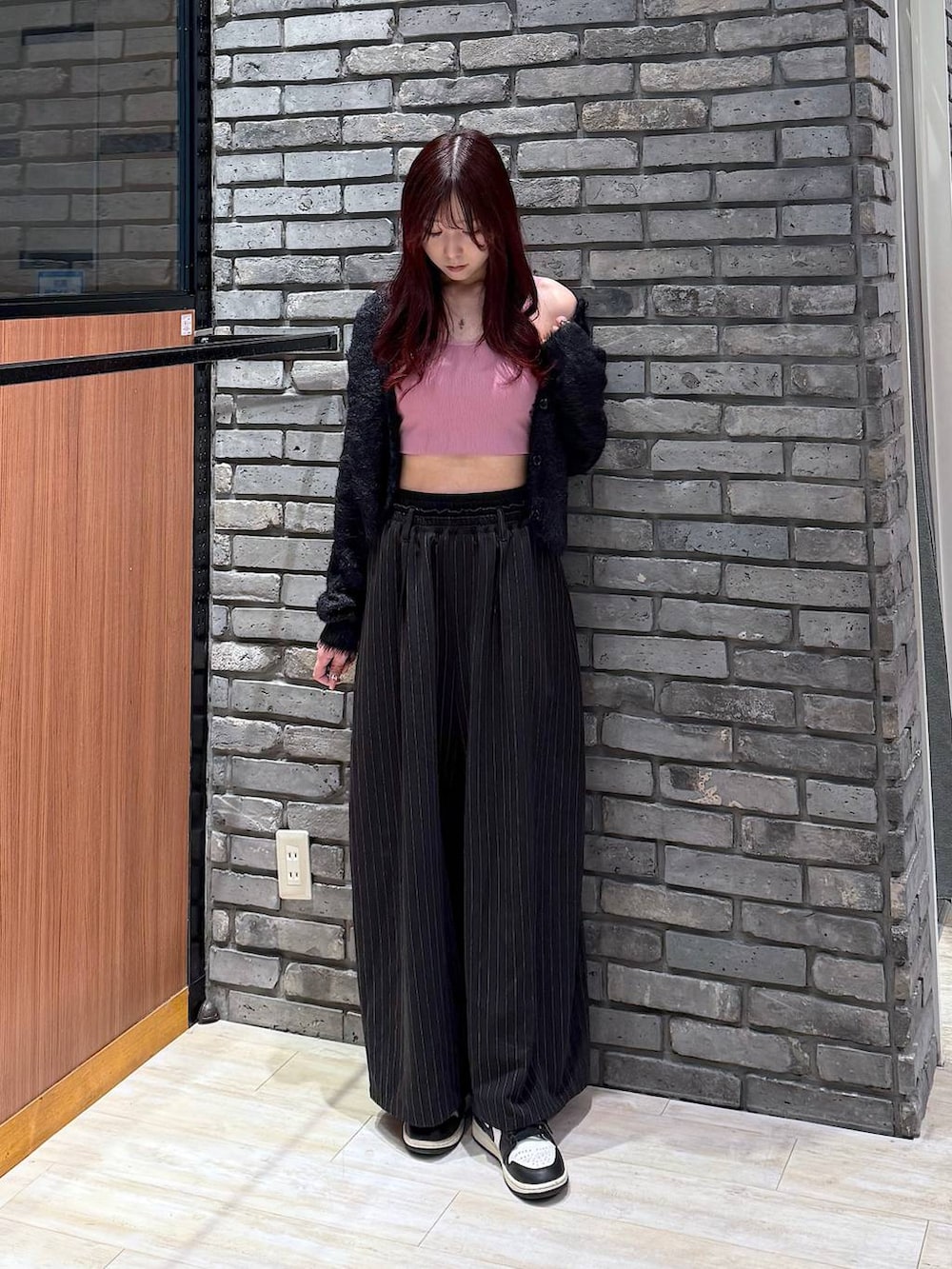 ピンク系のハンドバッグ、ブラック系のスラックス、ブラック系のニット/セーターを着用したレディースの冬コーディネートの2枚目の写真