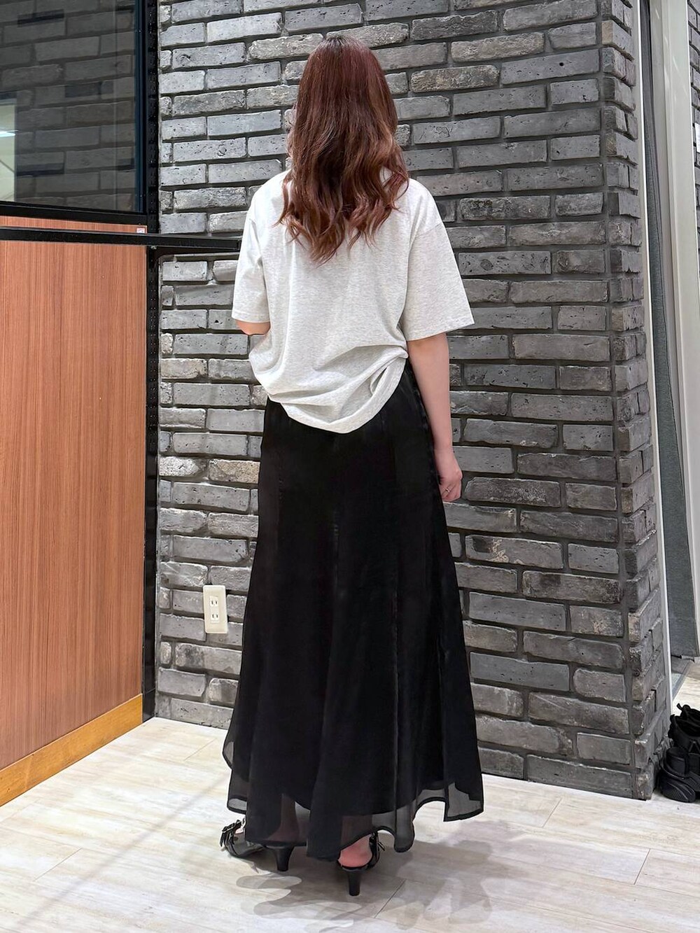 ブラック系のサンダル、ベージュ系のTシャツ/カットソー、ブラック系のスカートを着用したレディースの夏コーディネートの4枚目の写真