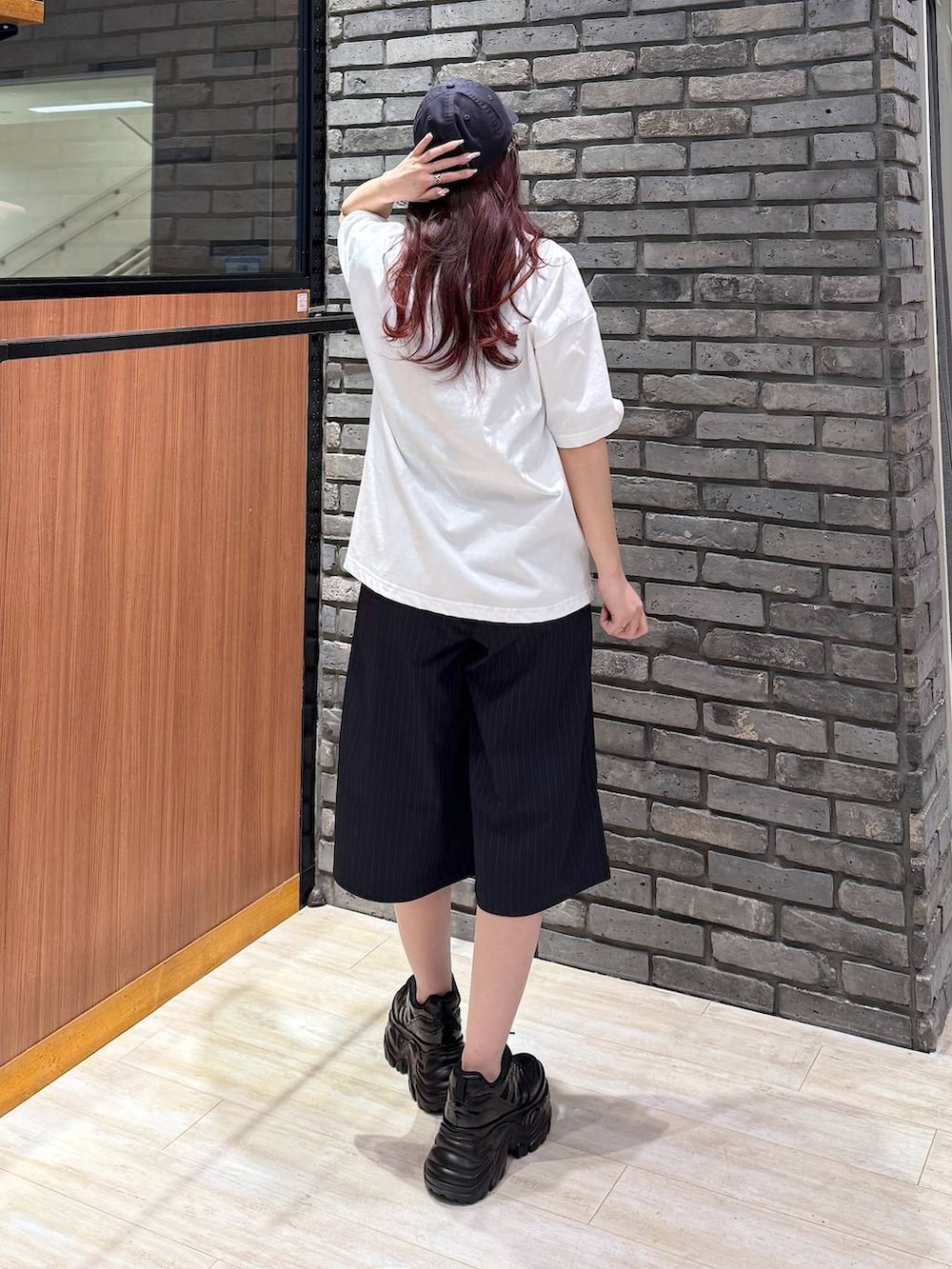 ブラック系のスニーカー、ホワイト系のTシャツ/カットソー、ブルー系のスラックスを着用したレディースの春コーディネートの3枚目の写真