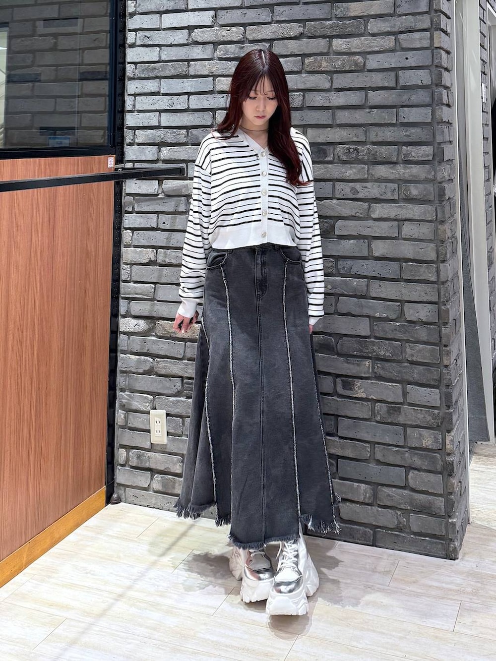 ホワイト系のブーツ、ブラック系のデニムスカート、ホワイト系のTシャツ/カットソーを着用したレディースの冬コーディネートの2枚目の写真