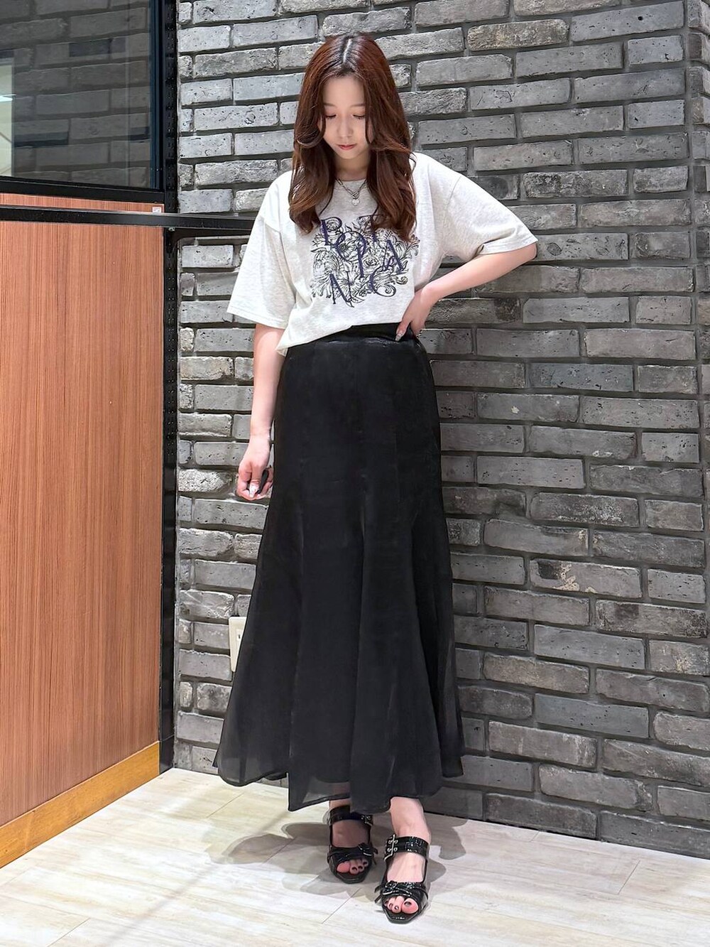 ブラック系のサンダル、ベージュ系のTシャツ/カットソー、ブラック系のスカートを着用したレディースの夏コーディネートの3枚目の写真