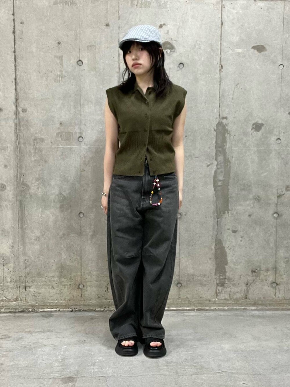 グレー系のデニムパンツ、ブラック系のサンダル、ブラウン系のニット/セーターを着用したレディースの夏コーディネートの2枚目の写真