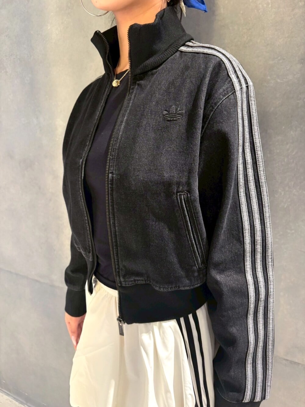 ブラック系のデニムジャケット、ホワイト系のスカート、ブラック系のスニーカーを着用したレディースの冬コーディネートの2枚目の写真