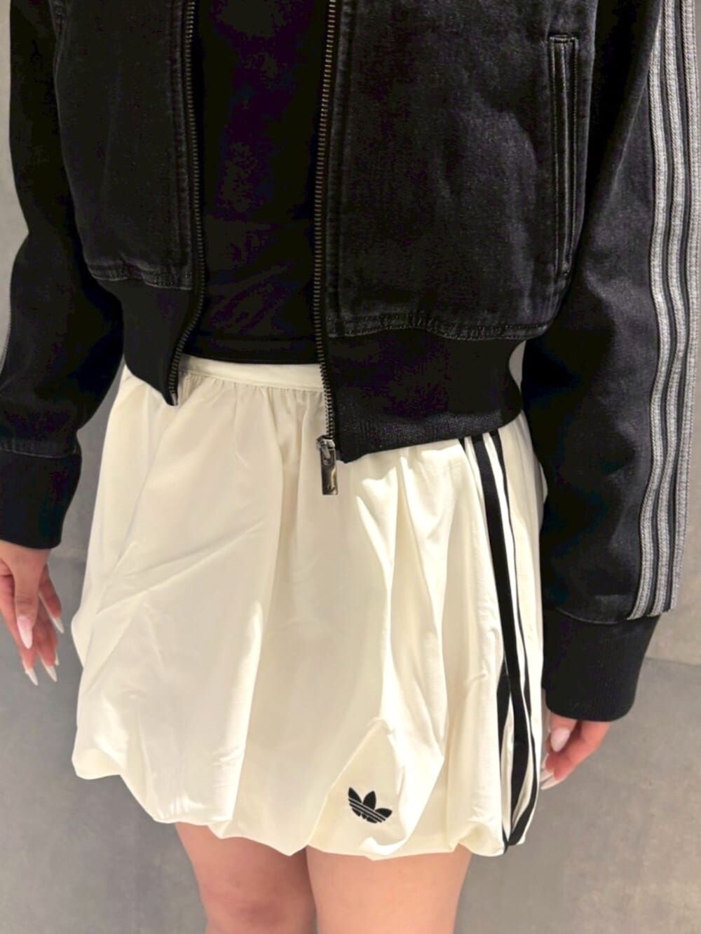 ブラック系のデニムジャケット、ホワイト系のスカート、ブラック系のスニーカーを着用したレディースの冬コーディネートの3枚目の写真