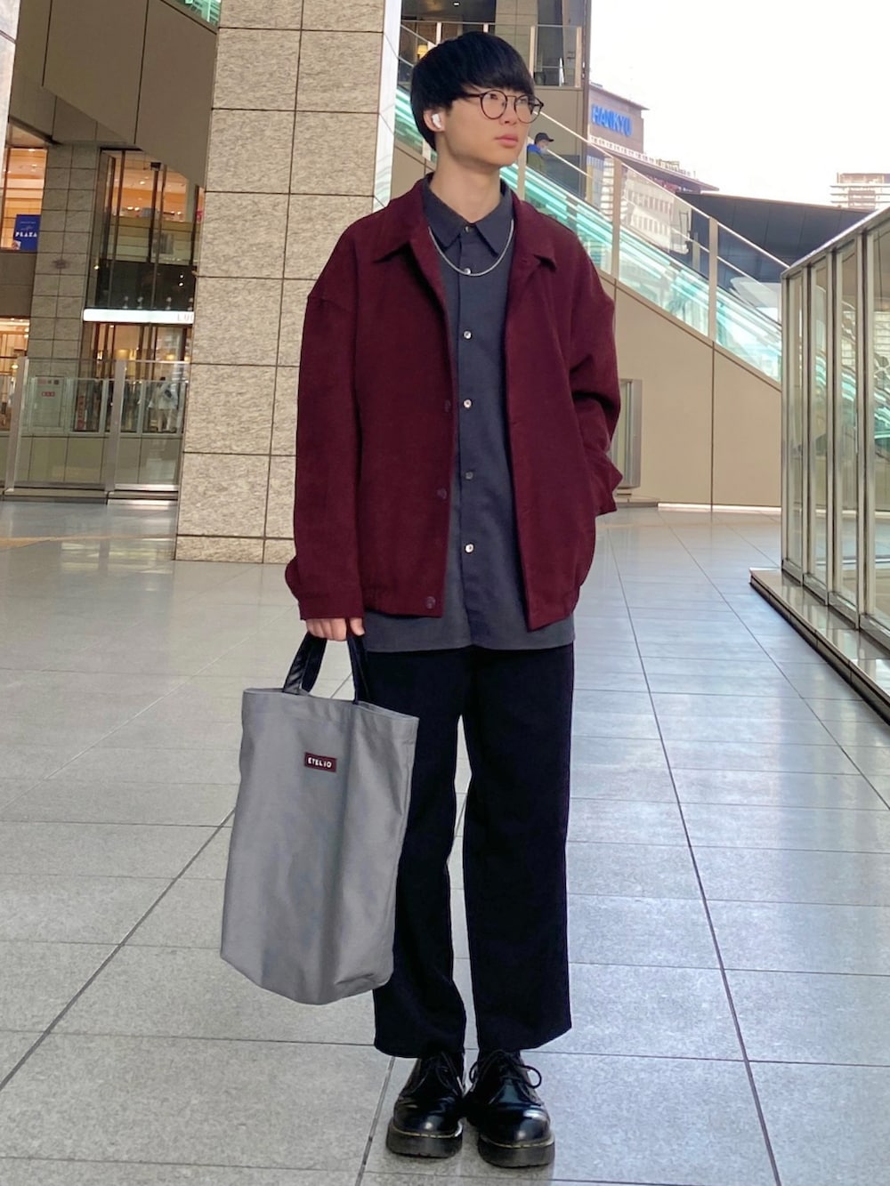 ブラック系のスラックス、ブラック系のドレスシューズ、グレー系のトートバッグを着用したメンズの春コーディネートの2枚目の写真